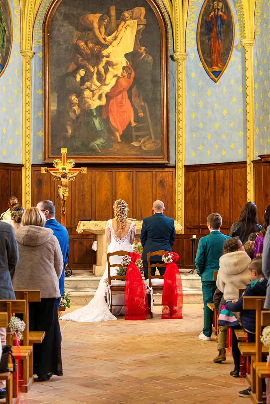 Alliance Solennelle - Cérémonie de Mariage à l'Église Vue arrière des mariés à l'autel d'une église, entourés de leurs invités et d'art sacré.
