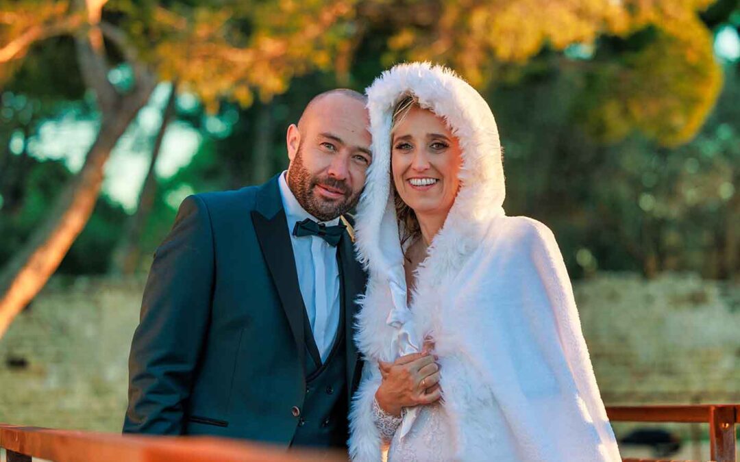 Couple de mariés enlacés dans une douce lumière de fin de journée, entourés par la nature.