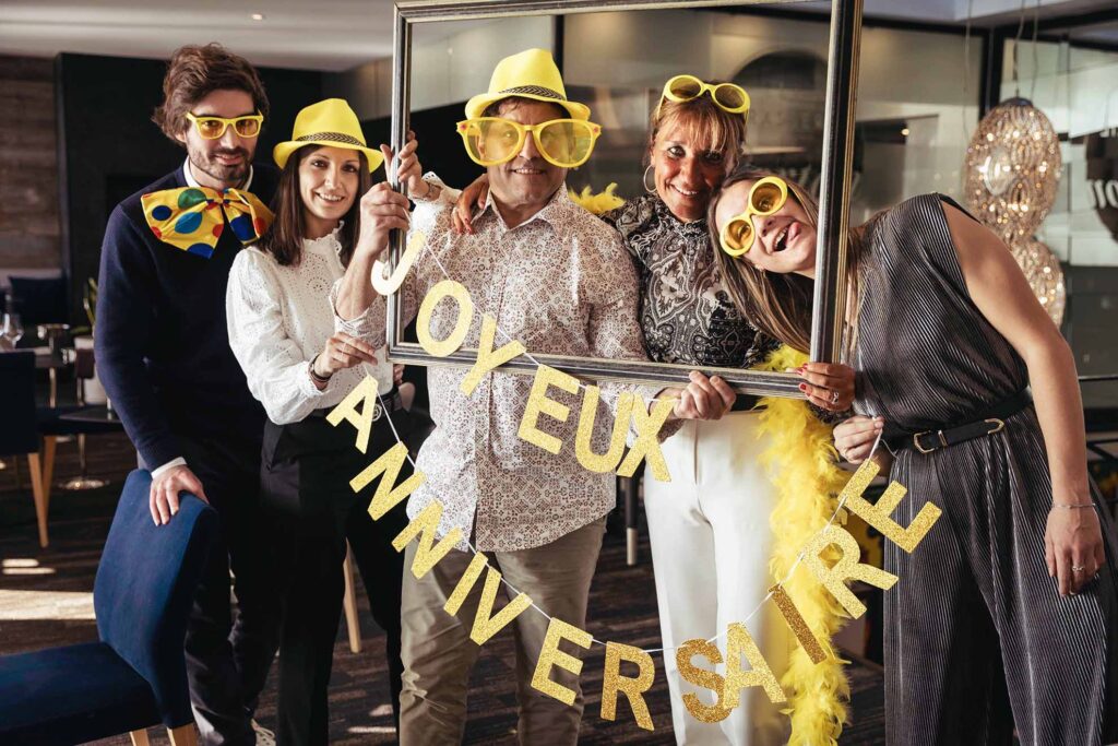 Groupe familial célébrant un anniversaire avec accessoires jaunes et cadre, capturé par un photographe à Aix-en-Provence.