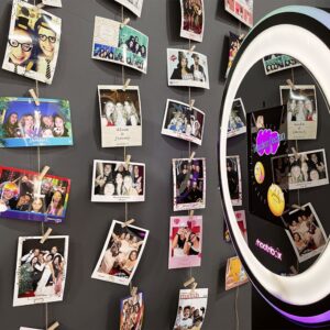Des photos souvenirs accrochées à un mur près d’un photobooth lors d’un événement d’entreprise