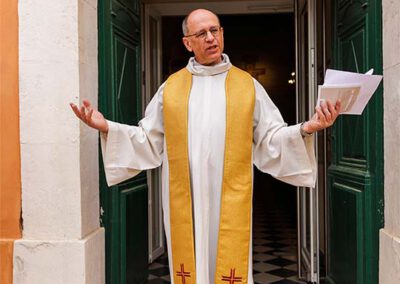 Le prêtre accueille les invités devant l’église d’Ensuès-la-Redonne avant la cérémonie du baptême de Léanza