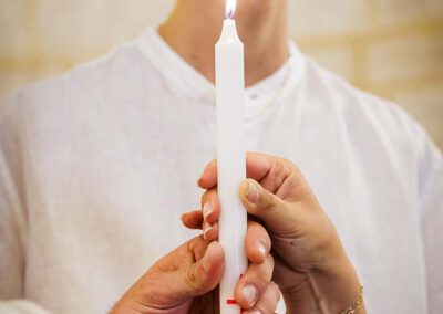 Plusieurs mains tiennent la bougie pendant la cérémonie du baptême de Léanza à Ensuès-la-Redonne
