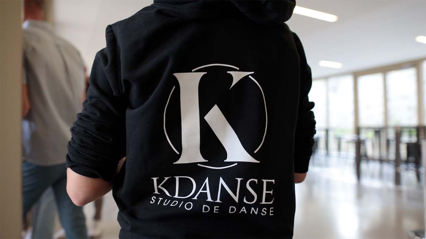 Vidéaste événementiel entreprise aix en provence 12 Danseuse de dos avec sweat noir au logo KDanse pendant les préparatifs du spectacle à Ensuès-la-Redonne