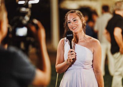 Photo, vidéo et duo photo + vidéo pour votre mariage à Aix-en-Provence 17 Une invitée souriante parle dans un micro pendant un enregistrement vidéo durant la soirée