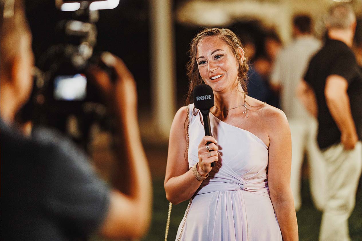 Photo, vidéo et duo photo + vidéo pour votre mariage à Aix-en-Provence 2 Une invitée souriante parle dans un micro pendant un enregistrement vidéo durant la soirée