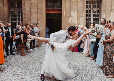 Photo, vidéo et duo photo + vidéo pour votre mariage à Aix-en-Provence 23 Les mariés s’embrassent à l’extérieur entourés de leurs invités après la cérémonie