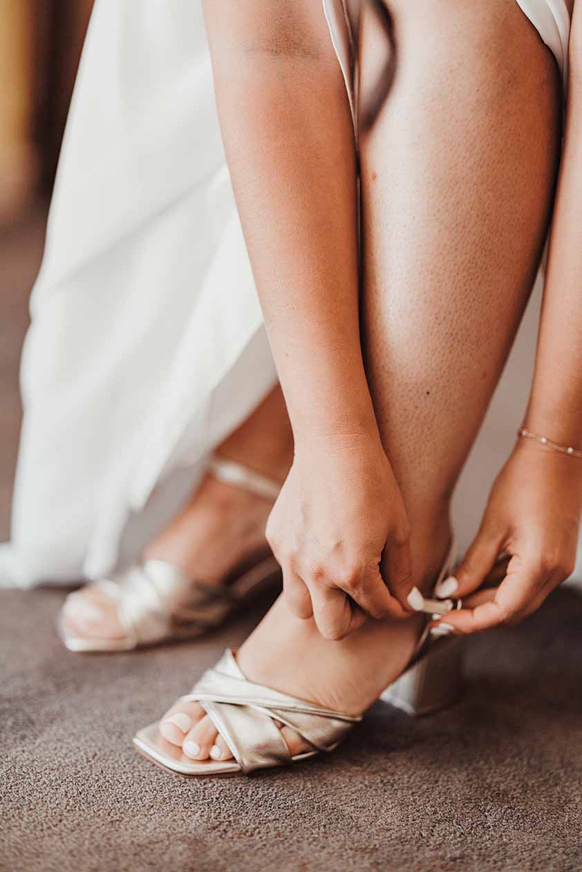 Détail des chaussures de la mariée La mariée attache sa chaussure à talon pendant les préparatifs