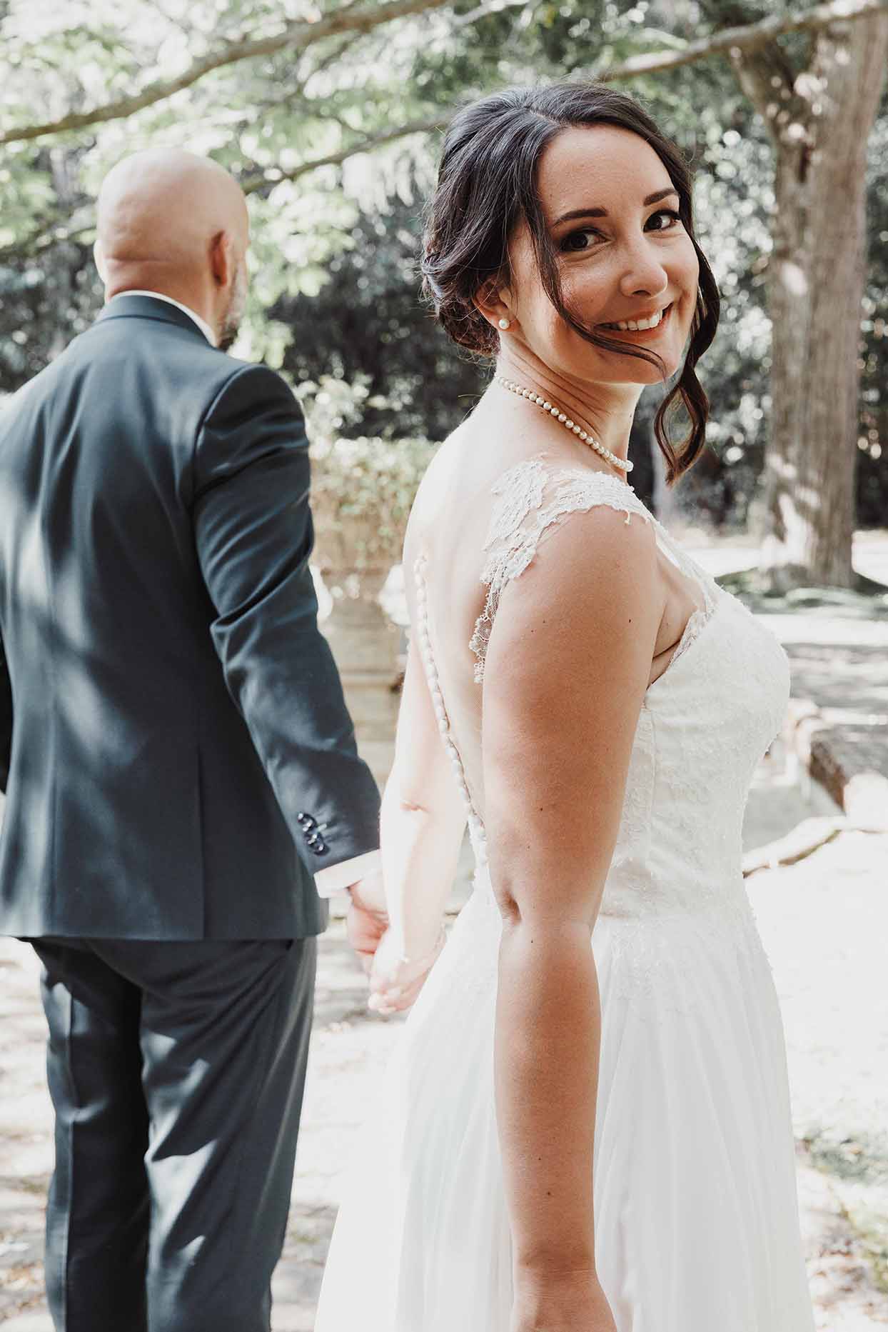 La mariée se retourne vers l’objectif La mariée se retourne en souriant tout en tenant la main du marié