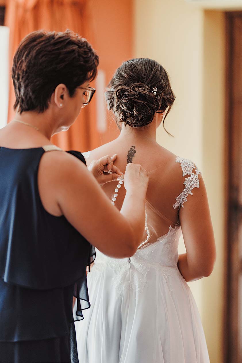 La robe de la mariée fermée avant la cérémonie Une proche ferme la robe de la mariée vue de dos pendant les préparatifs