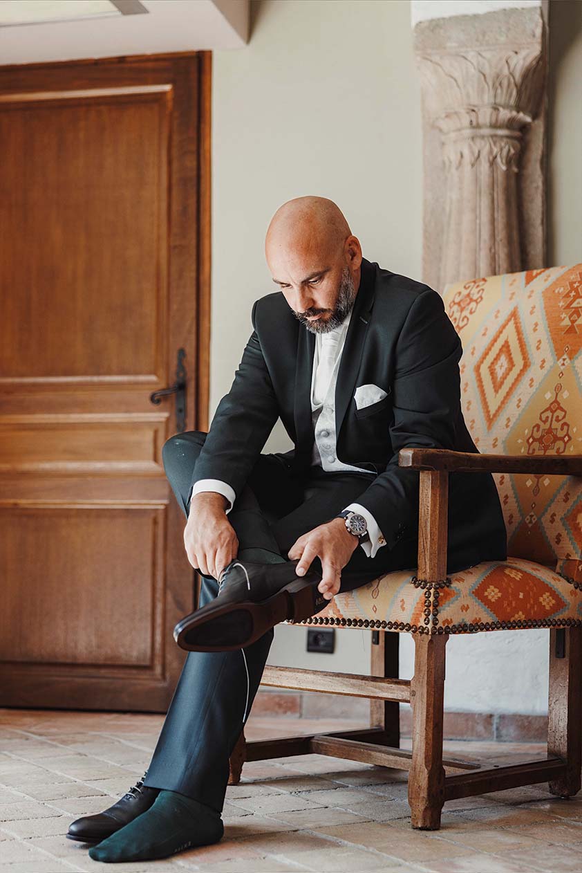 Le marié se prépare avant la cérémonie Le marié assis sur une chaise met sa chaussure pendant les préparatifs
