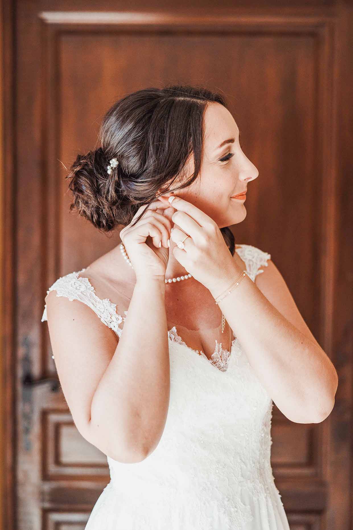 Préparatifs de la mariée avant le mariage La mariée met sa boucle d’oreille pendant les préparatifs