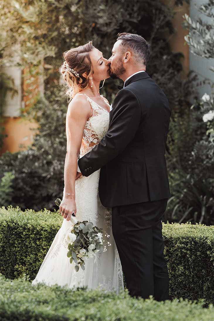 Baiser des mariés après le mariage civil Les mariés s’embrassent dans un jardin après leur mariage civil à Aix-en-Provence.
