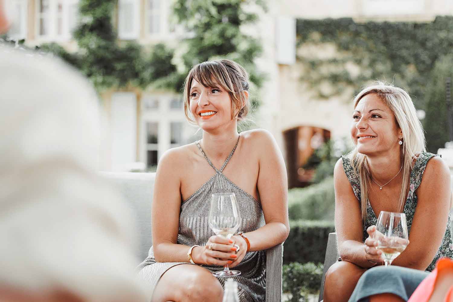 Invitées pendant le cocktail de mariage Deux invitées souriantes pendant un cocktail de mariage en extérieur