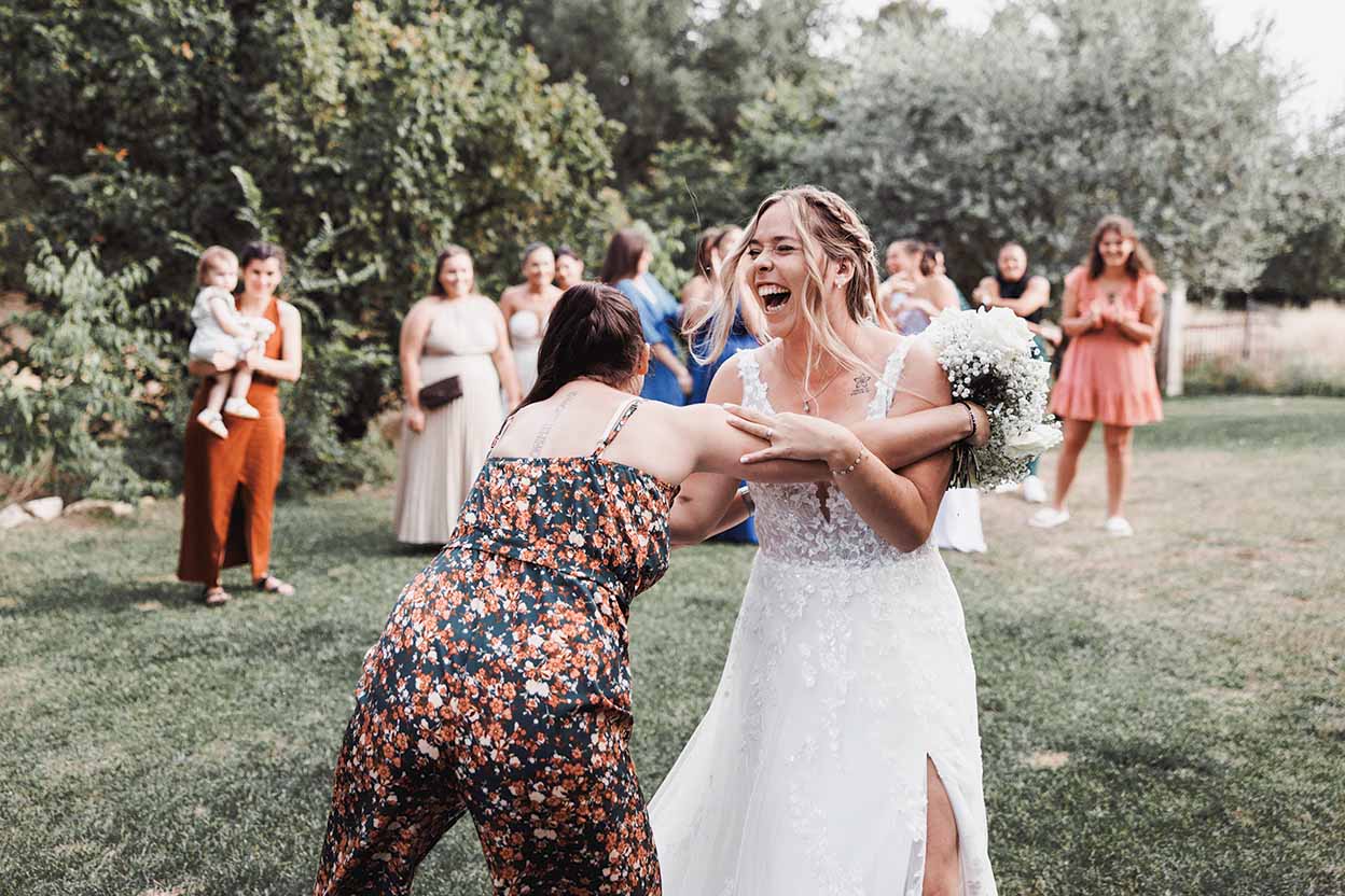 Mariée riant avec ses invités Mariée riant avec une invitée pendant un moment spontané en extérieur