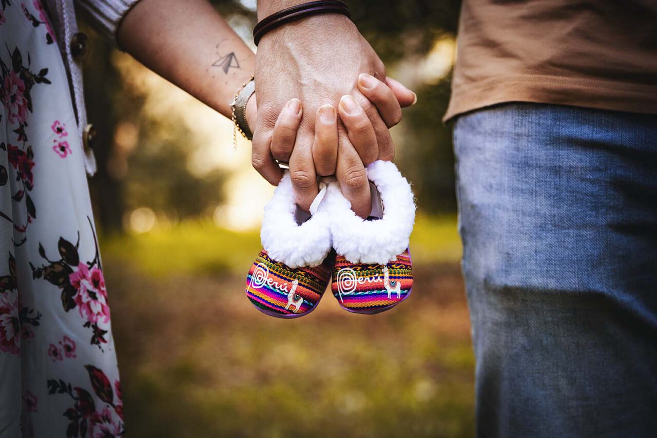 Photographe grossesse Martigues : futurs parents tenant des chaussons de bébé