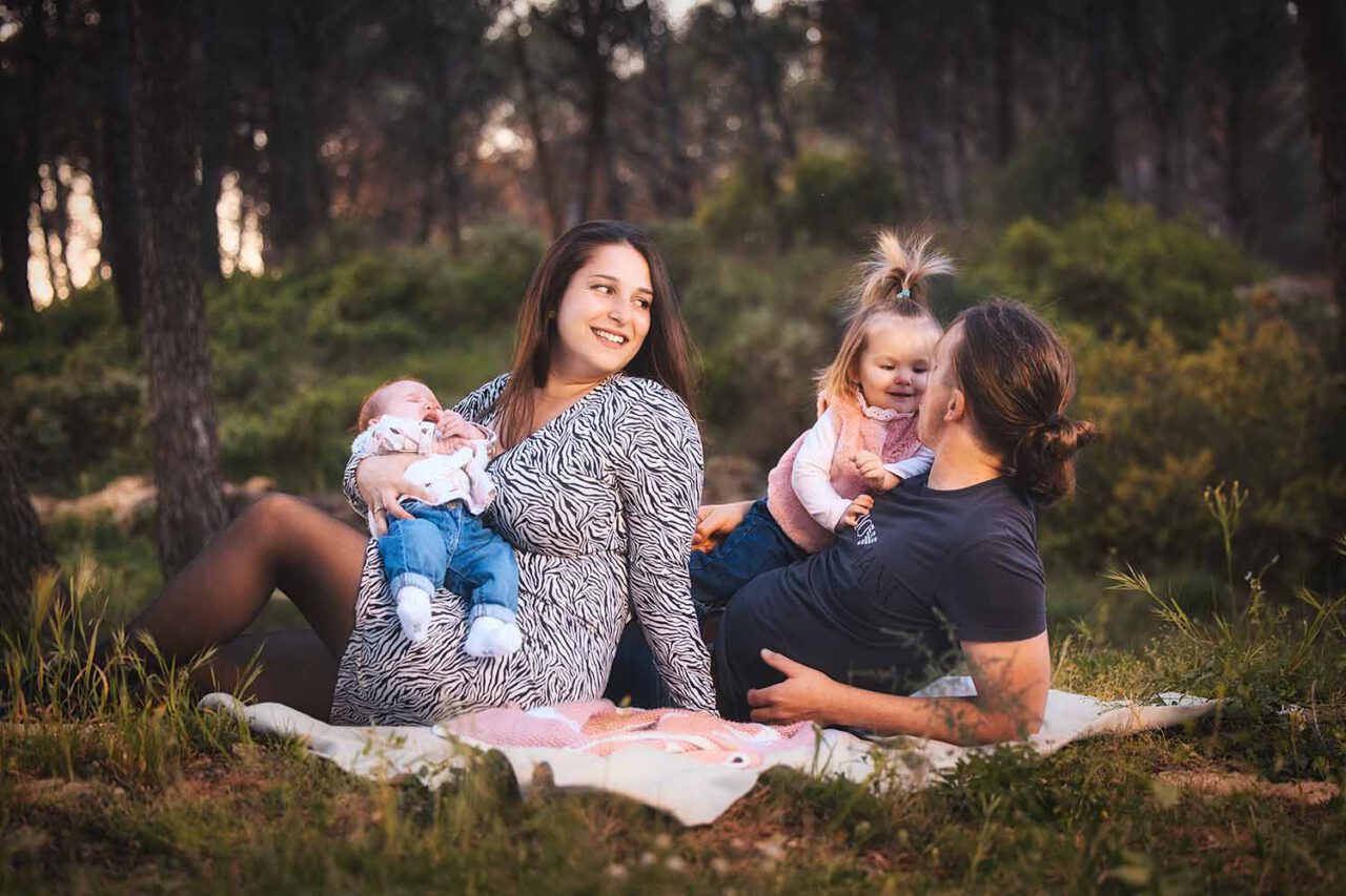 Photographe famille Miramas : famille assise dans les bois avec bébé et enfant